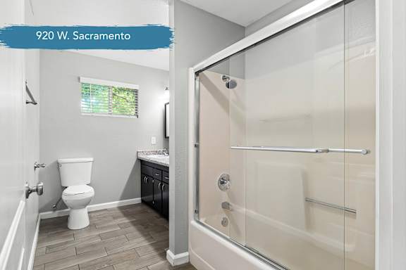 Bathroom with sliding glass tub enclosure and toilet at OSM Properties Homes & Apartments, Chico