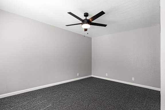 Empty bedroom with ceiling fan and gray carpet at OSM Properties Homes & Apartments, California, 95926