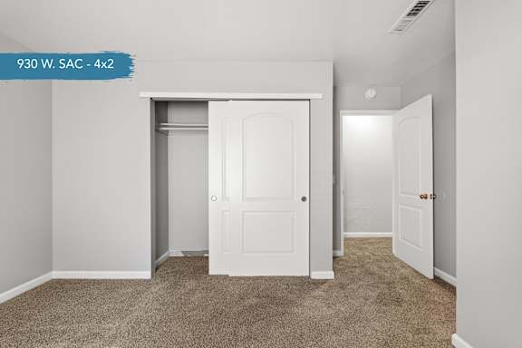 A room with a carpeted floor and a white door.