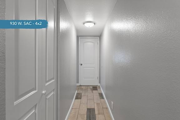 A hallway with a door at the end and a tiled floor.