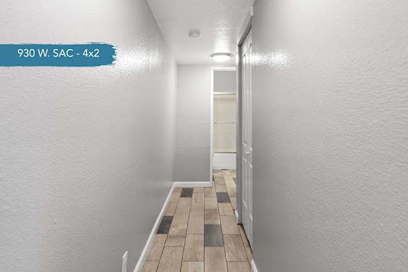 A long hallway with a white wall and a wooden floor.