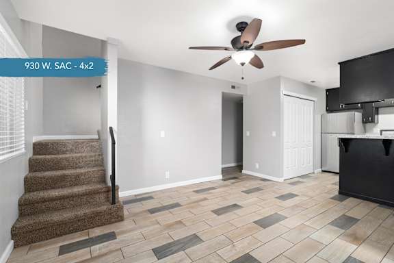 A living room with a staircase and a ceiling fan.