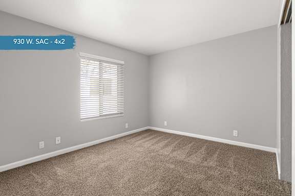 A room with a carpeted floor and a window with blinds.