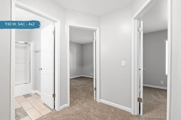 A white room with a carpeted floor and a doorway leading to another room.