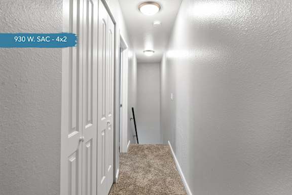 A hallway with a carpeted floor and white walls.