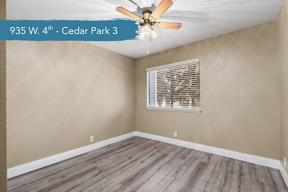 A room with a ceiling fan and a window with blinds.