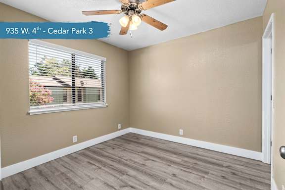 A room with a ceiling fan and a window with blinds.