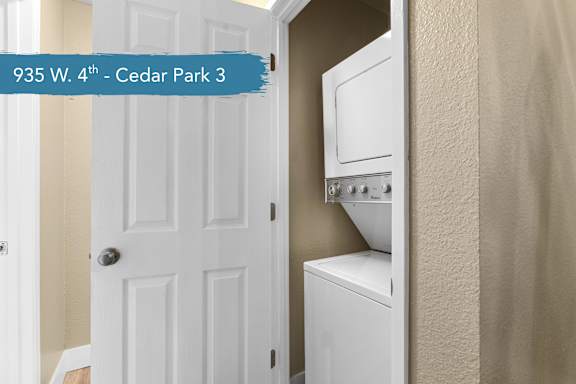 A white door is open to a small kitchen with a white oven and microwave.