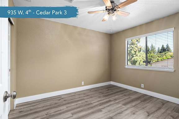 A room with a ceiling fan and a window with blinds.