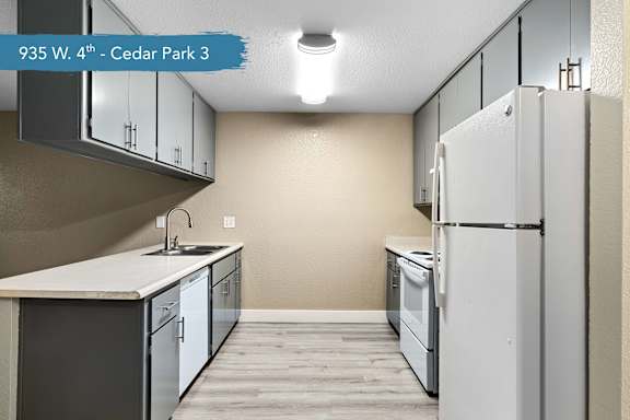 A kitchen with a white refrigerator, white countertop, and white cabinets.