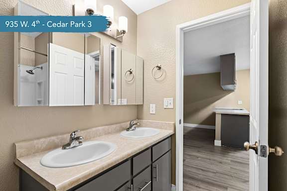 A bathroom with a double sink vanity and a mirror above it.