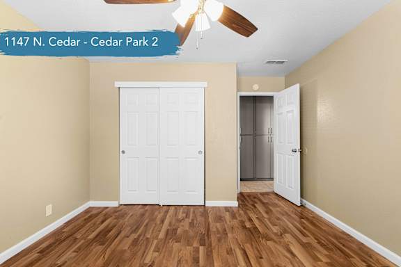 A room with a white door and a ceiling fan.