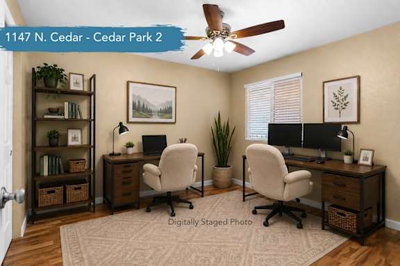 A room with two desks and two chairs, a ceiling fan, and a rug on the floor.