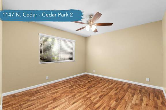 A room with a ceiling fan and wooden flooring.