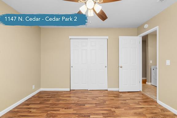 A room with a ceiling fan and three doors.