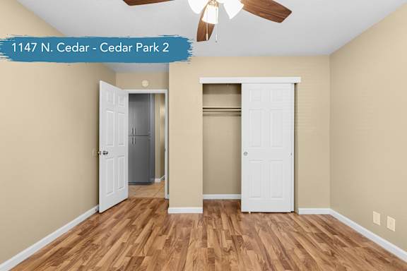 A room with a ceiling fan and two doors, one of which is open.