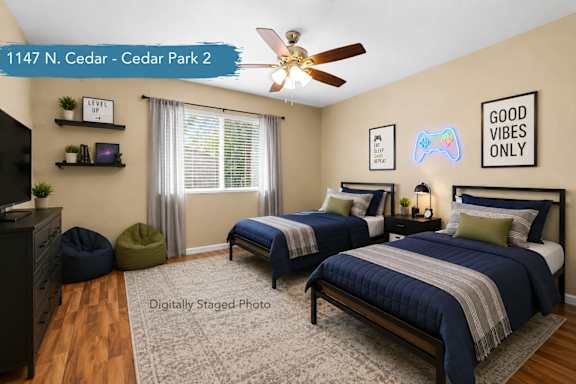 A bedroom with two beds, a ceiling fan, and a "Good Vibes Only" sign on the wall.