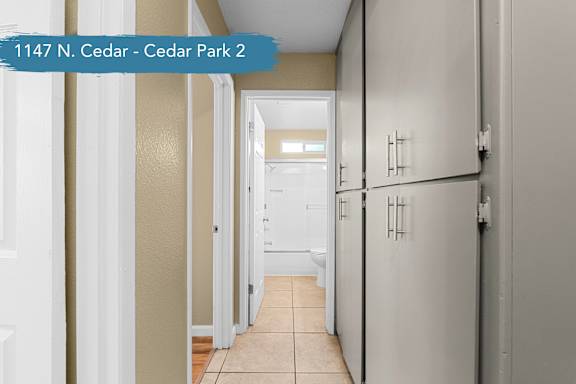 A hallway with doors on both sides leading to a bathroom.