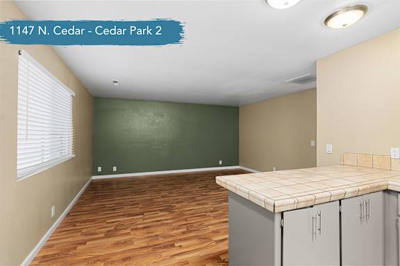 A room with a wooden floor and a counter with cabinets.