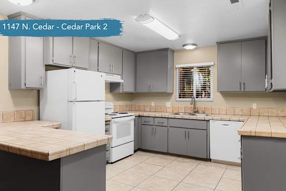 A kitchen with a white refrigerator and cabinets.