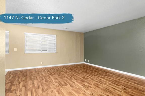 A room with wooden flooring and a window with blinds.