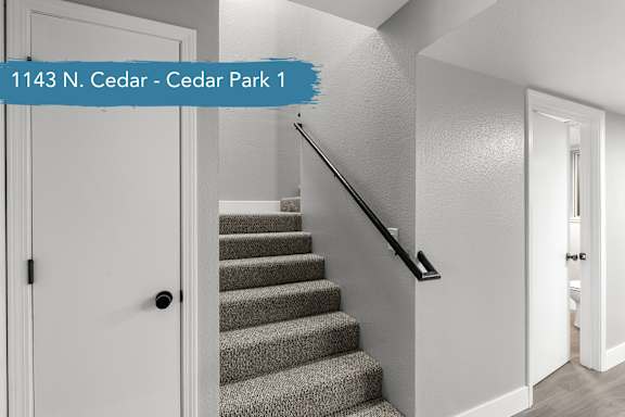 A staircase with a black handrail and a white door on the left.
