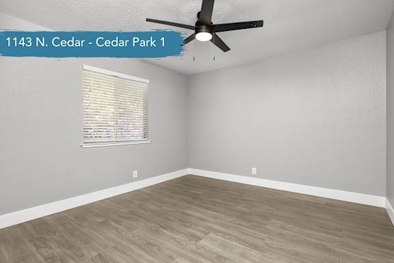 A room with a ceiling fan and a window with blinds.