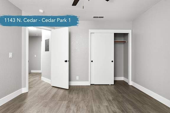 A spacious room with two white doors and a wooden floor.