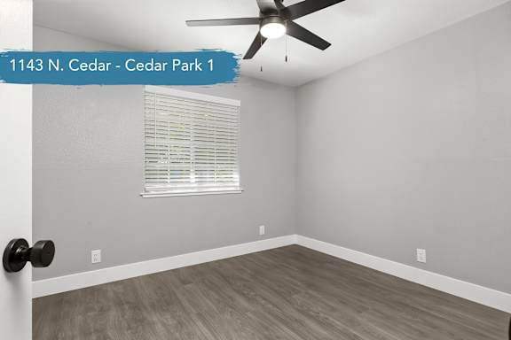A room with a ceiling fan and a window with blinds.