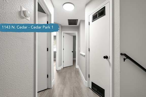 A hallway with doors on both sides and a sign that reads "1143 N. Cedar - Cedar Park 1".