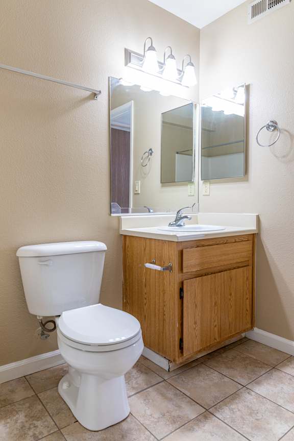 Bathroom with oak vanity and toilet at Redwood Cove Apartments, Chico