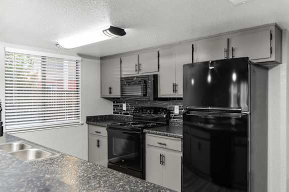 Kitchen with modern black appliances and speckled countertops at Redwood Cove Apartments, Chico, CA 95928