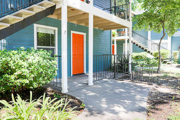 Apartment entrance with orange door and concrete patio at Redwood Cove Apartments, Chico, CA