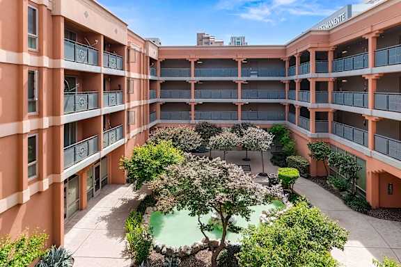 A courtyard with a tree and bushes surrounded by buildings at Pin Yuen, Sacramento, CA