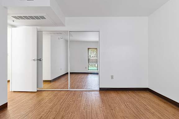 A room with white walls and wooden flooring with a sliding glass door at Pin Yuen, Sacramento, CA