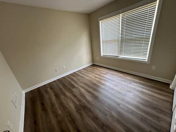 A room with wooden flooring and a window with blinds at Zora Encanto apartments.