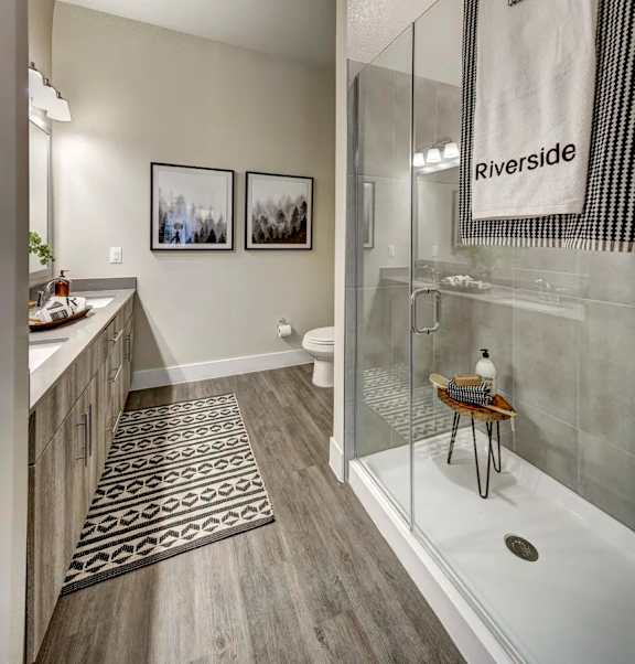 A bathroom with a glass shower stall and a towel hanging on the glass door at Arise Riverside Apartments, Austin, TX, 78741