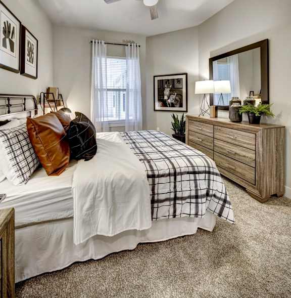 A bedroom with a bed, dresser, and mirror at Arise Riverside Apartments, Texas 78741