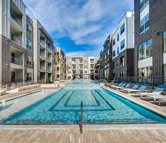 A long rectangular pool in the middle of a courtyard surrounded by buildings at Arise Riverside Apartments, Austin, Texas
