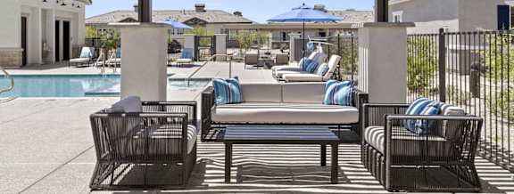 a poolside lounge area with chairs and umbrellas
