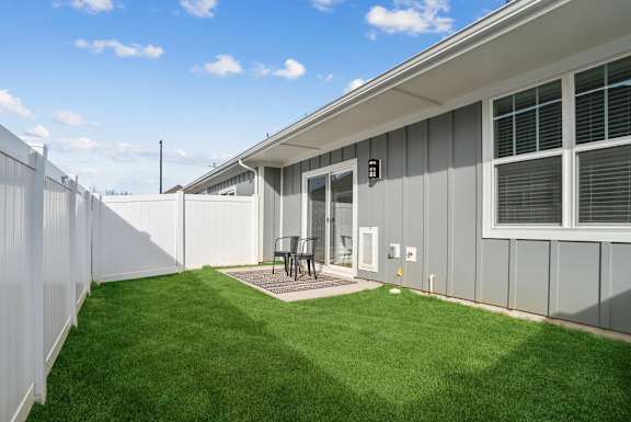 A small backyard with a white fence and a grey house at Zora University homes in Charlotte, NC.