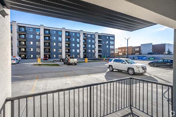 A white car is parked in a parking lot in front of a building.at Hills on 36, Edmonton, AB