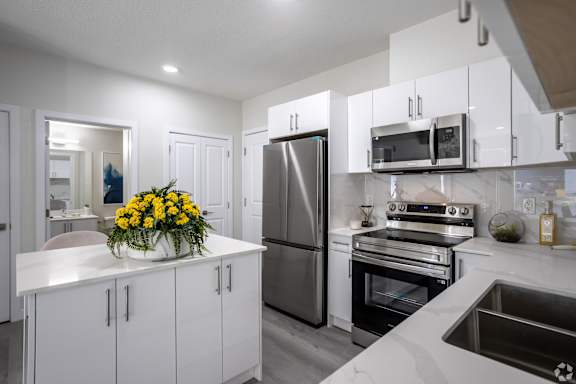 A modern kitchen with white cabinets and stainless steel appliances.at Hills on 36, Edmonton, AB T6X 3K2