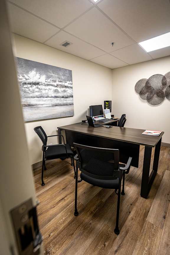 an office with a desk and chairs and a painting on the wall