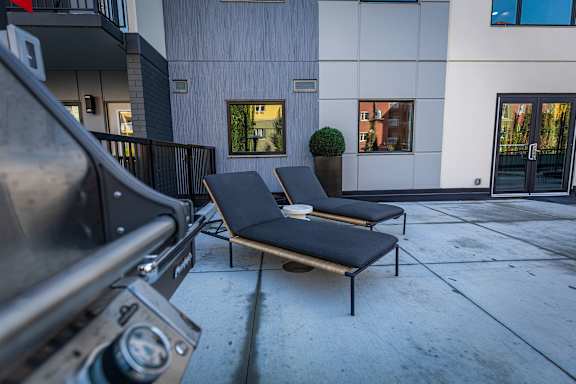 two lounge chairs on the sidewalk in front of a building