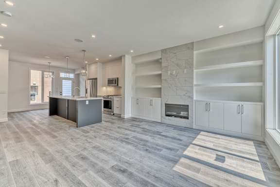 A spacious kitchen with a grey island and white cabinets.
