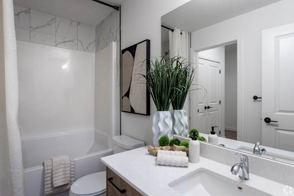A white bathroom with a white toilet and a white sink.at The Pointe at Riverview, Edmonton