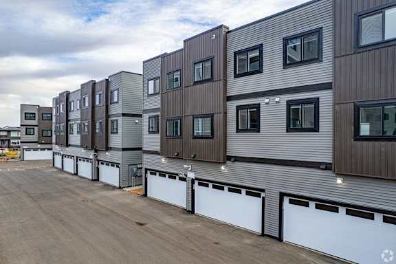 A series of modern townhouses with garages in front.at The Pointe at Riverview, Edmonton, T6M 3H4