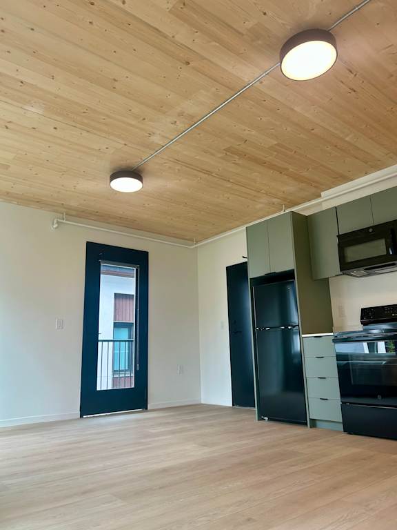A kitchen with a black fridge and stove top oven.