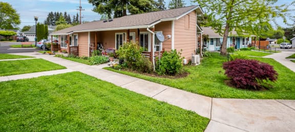 a small pink house with a sidewalk in front of it